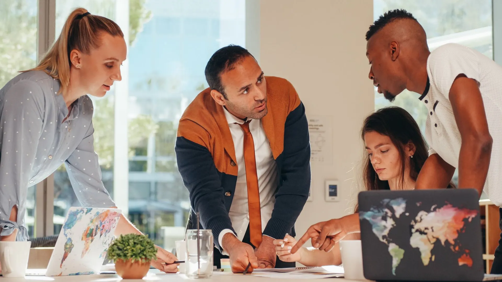 Multicultural group engaged in teamwork with laptops in a modern office.
