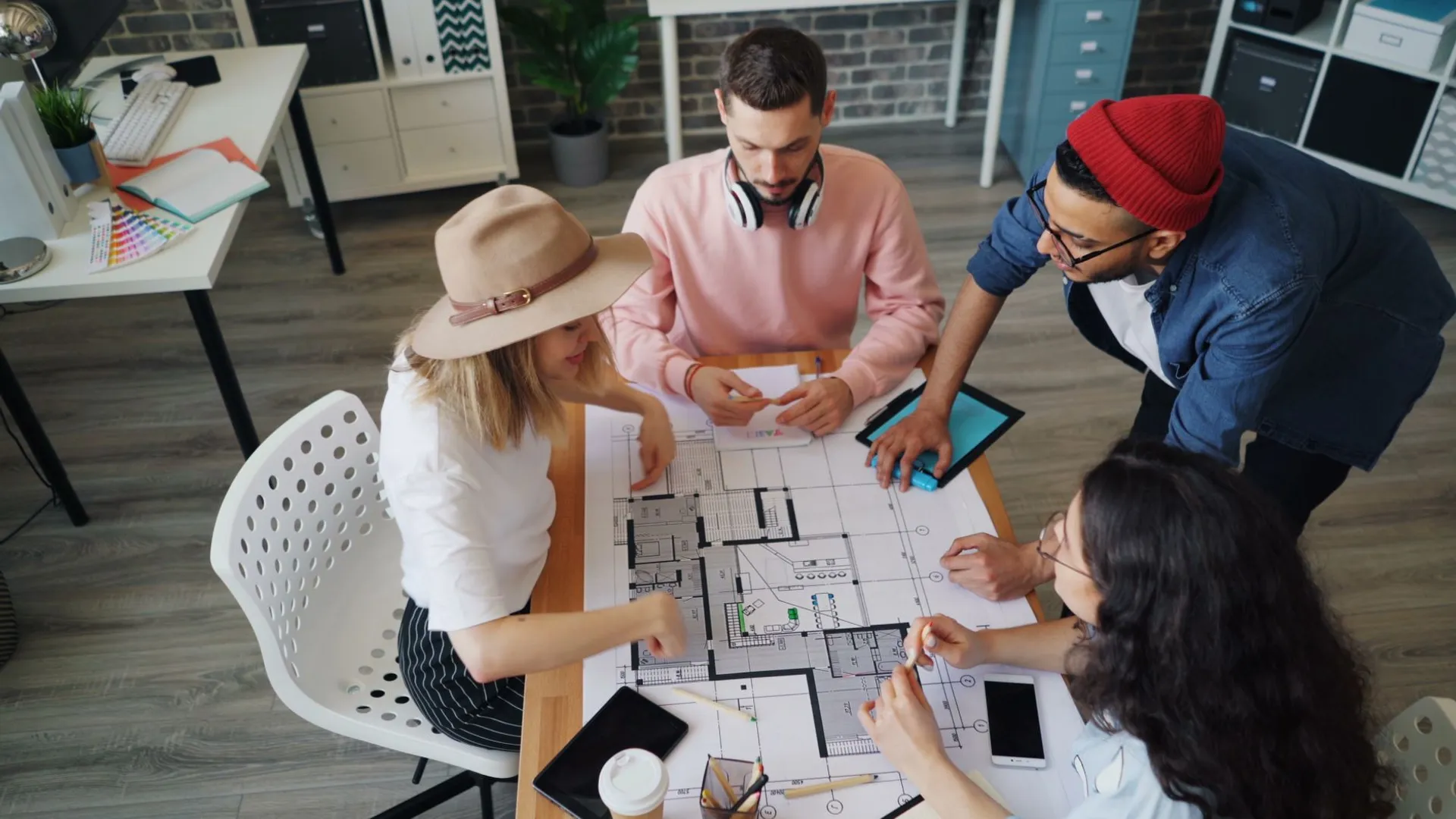 Group of diverse individuals working on architectural plans in a modern office setting.