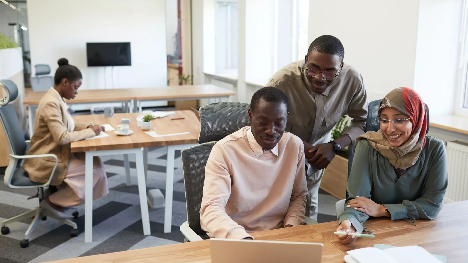 A diverse group of coworkers engaged in teamwork and collaboration in a modern office setting.