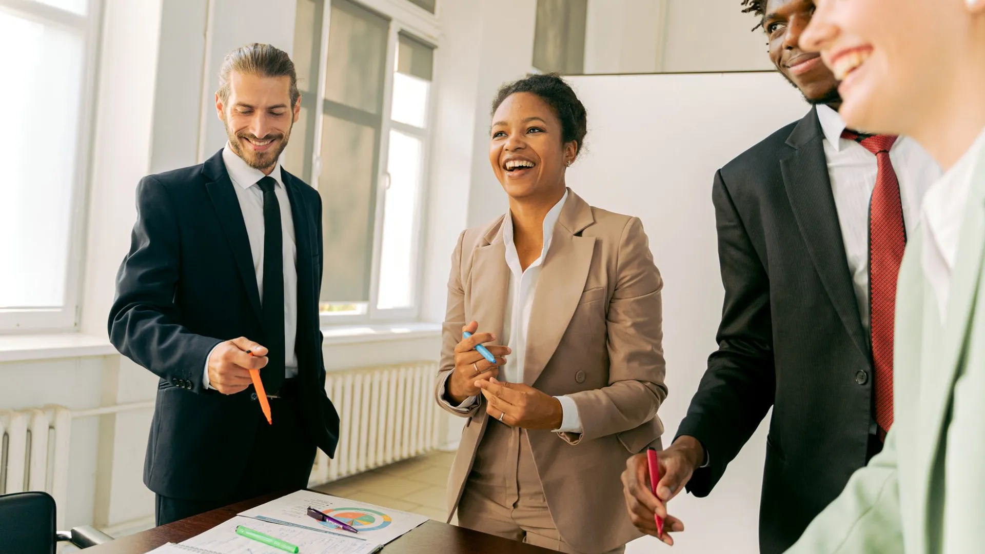 A diverse group of professionals collaborating in a bright office setting, engaging in teamwork and discussion.
