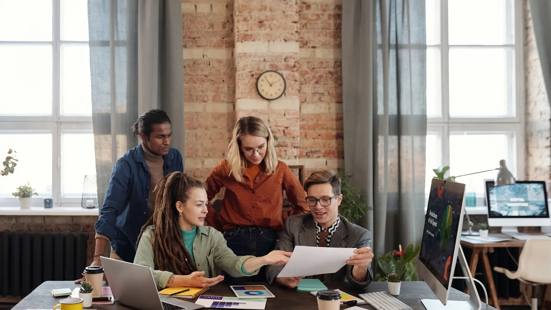 A diverse team of young professionals working on a business strategy in an urban office setting.