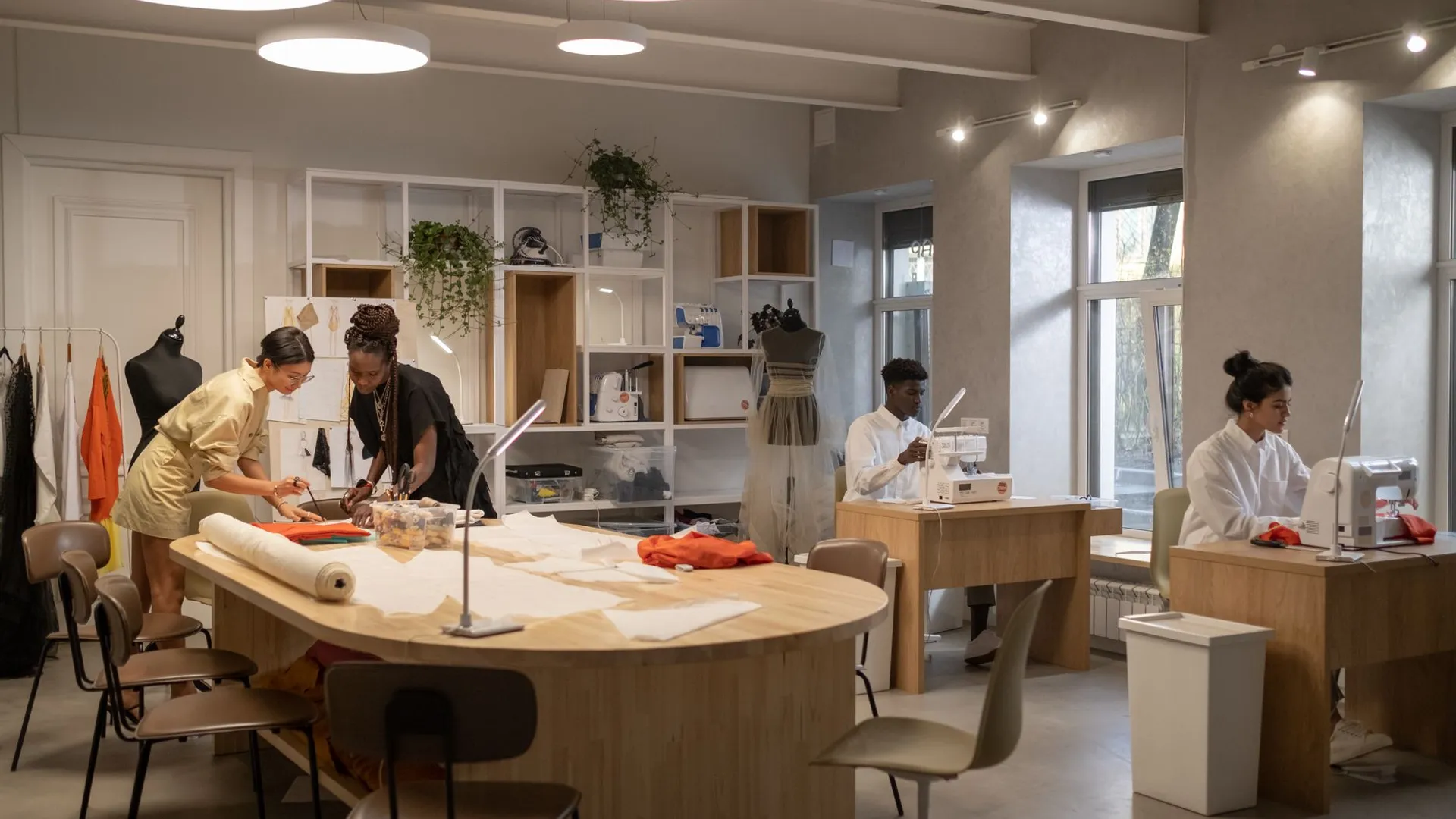 Fashion designers working together in a modern atelier with sewing machines and patterns.