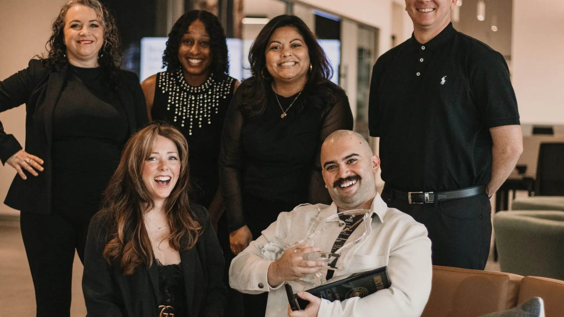 Diverse group of real estate professionals posing confidently in office environment.